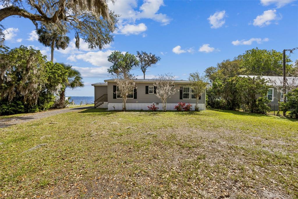 A single-story manufactured home sits on a grassy lot near a body of water — 108 SANDRA LANE, CRESCENT CITY, FL