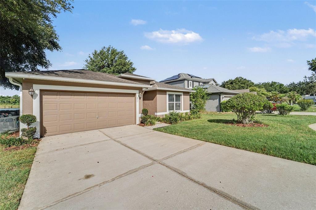 A tan single-story house with a two-car garage and a concrete driveway — 817 LAKE DOE BOULEVARD, APOPKA, FL