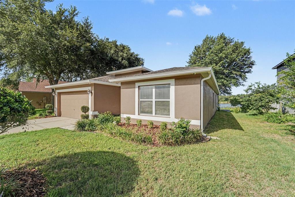 A single-story house with a tan stucco exterior, a two-car garage, and a front garden — 817 LAKE DOE BOULEVARD, APOPKA, FL