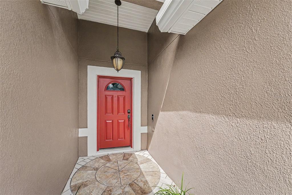 A red front door is set within a recessed entryway featuring a circular stone medallion — 817 LAKE DOE BOULEVARD, APOPKA, FL