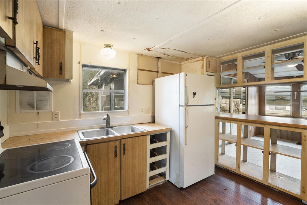 A kitchen with wood-look cabinets, a white refrigerator, a double sink, and unfinished shelving — 108 CHERYL ELAINE DRIVE, BUNNELL, FL