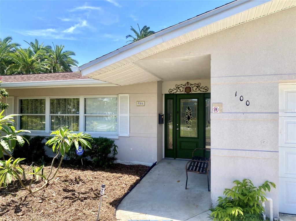 The exterior of a single-story house features a green front door and a concrete walkway — 100 59TH AVENUE S, ST PETERSBURG, FL