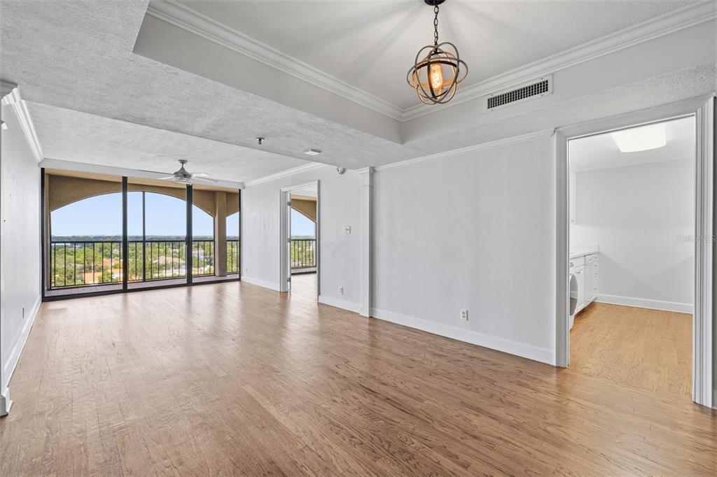 An empty living room with hardwood floors, a tray ceiling, and a balcony with views — 3211 W SWANN AVENUE UNIT 1103, TAMPA, FL