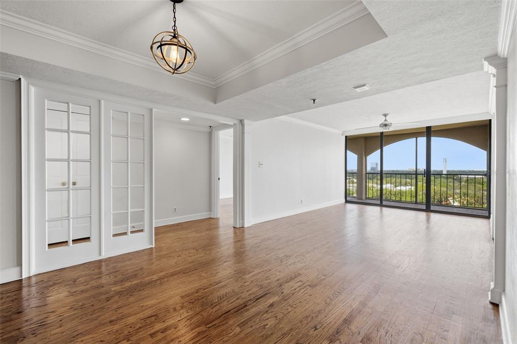 An empty room with hardwood floors, a tray ceiling, French doors, and a balcony view — 3211 W SWANN AVENUE UNIT 1103, TAMPA, FL