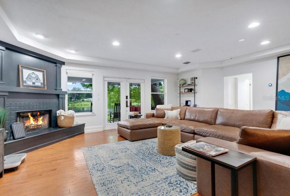 A living room features a dark fireplace, a large brown sectional, and glass patio doors — 2227 HOWARD DRIVE, WINTER PARK, FL