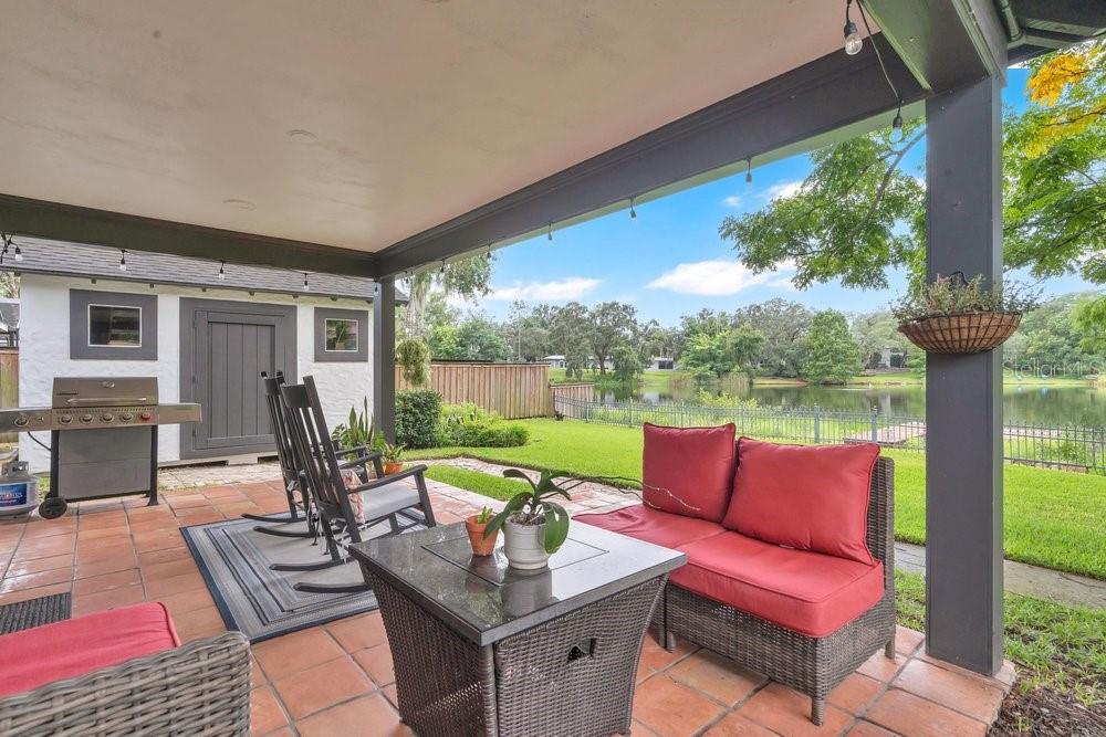 A covered patio with tile flooring, outdoor furniture, and a view of a lake — 2227 HOWARD DRIVE, WINTER PARK, FL
