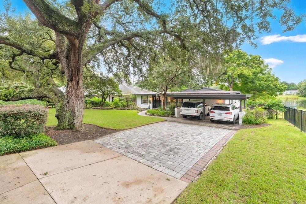 A paved driveway leads to a house with a carport and large oak trees — 2227 HOWARD DRIVE, WINTER PARK, FL