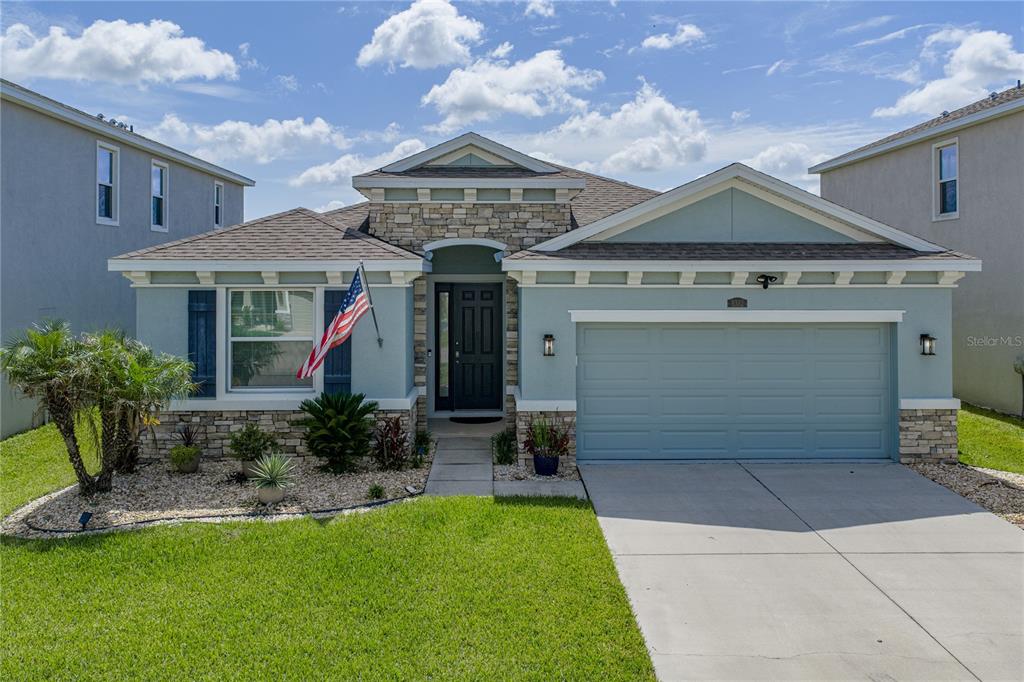 A single-story house with a stone facade, blue siding, and a two-car garage — 8382 BOWER BASS CIRCLE, WESLEY CHAPEL, FL