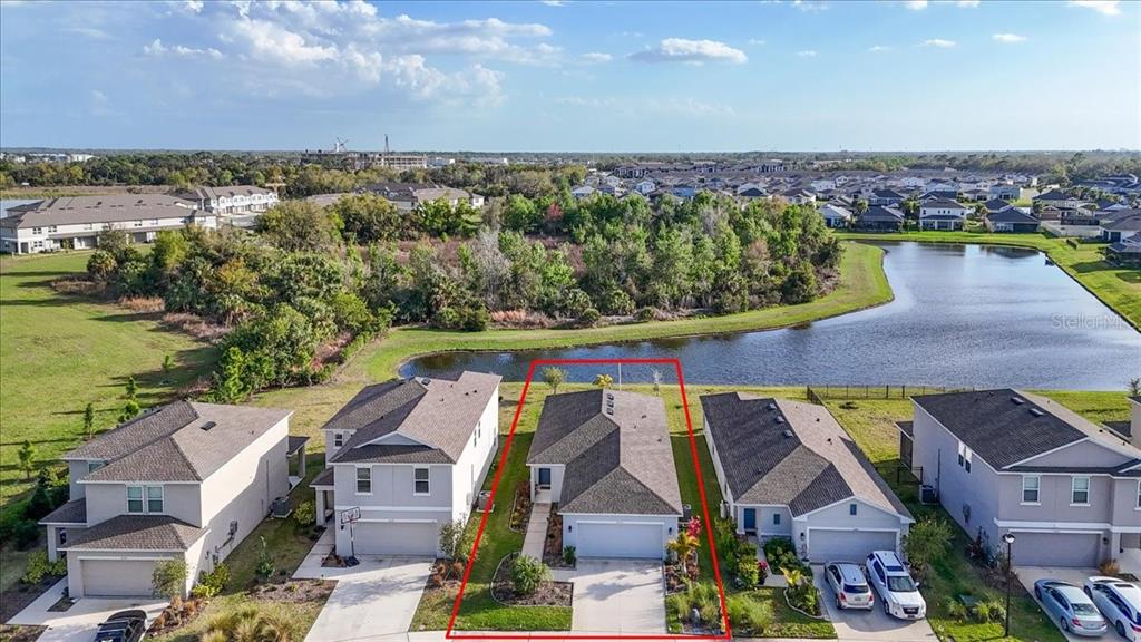 An aerial view shows a single-story house with a two-car garage and a backyard pond — 6333 MILESTONE LOOP, PALMETTO, FL