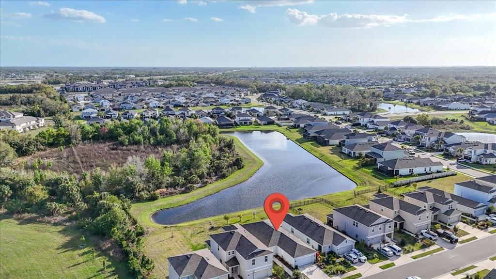 An aerial view shows a suburban neighborhood with houses bordering a large retention pond — 6333 MILESTONE LOOP, PALMETTO, FL
