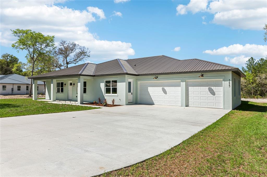 A light green single-story house with a metal roof and a two-car garage — 351 MITNIK DRIVE, DELTONA, FL