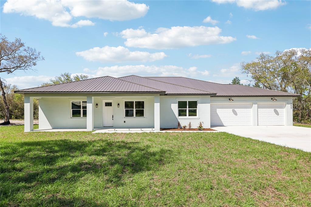 A single-story white house with a metal roof and a three-car garage — 351 MITNIK DRIVE, DELTONA, FL