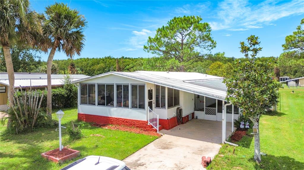 A single-story mobile home with a red brick base, screened porch, and attached carport — 2614 MC DANIEL DRIVE, KISSIMMEE, FL