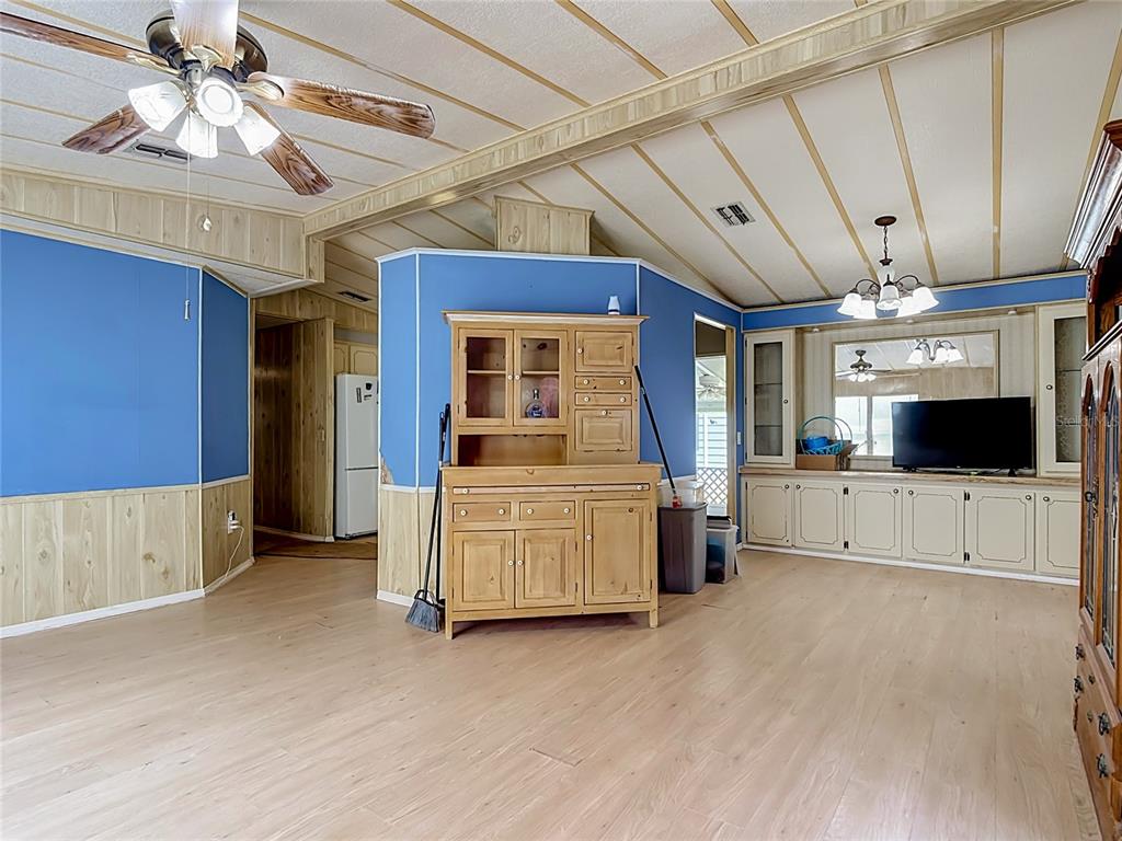 A living room features blue walls, wood paneling, light-colored flooring, and a wooden hutch — 2614 MC DANIEL DRIVE, KISSIMMEE, FL