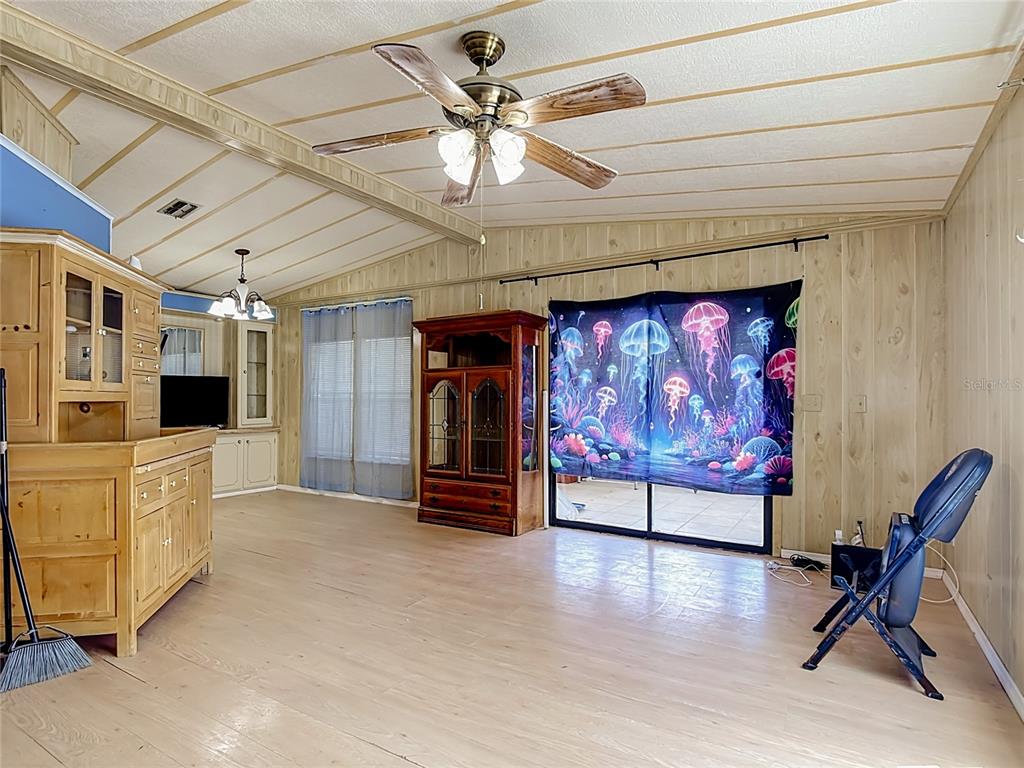 A living room features wood-paneled walls, a ceiling fan, a large hutch, and a jellyfish tapestry — 2614 MC DANIEL DRIVE, KISSIMMEE, FL