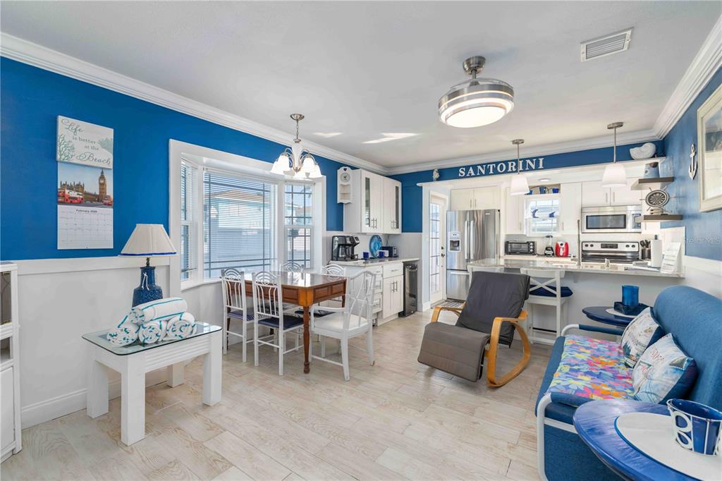 A kitchen and dining area features blue walls, white cabinetry, and light wood-look flooring — 111 9TH STREET N, BRADENTON BEACH, FL