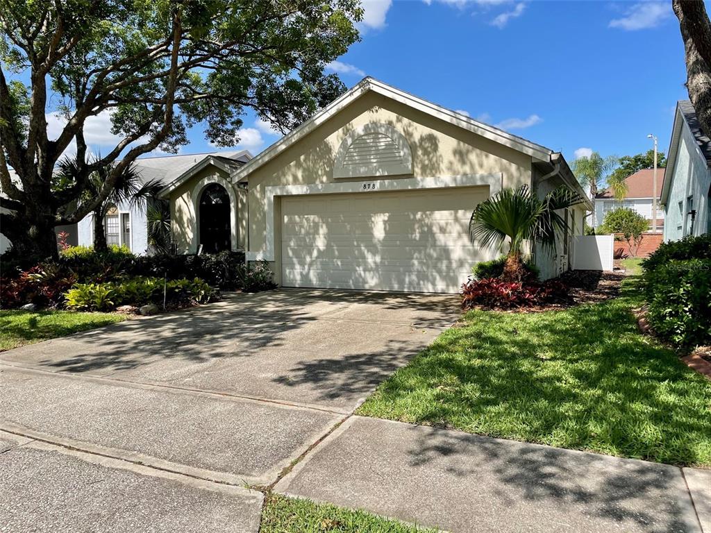 A single-story house with a beige exterior, a two-car garage, and a concrete driveway — 878 E CHARING CROSS CIRCLE, LAKE MARY, FL