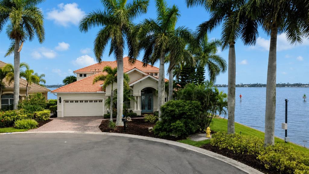 A patio features a stone hot tub and infinity pool overlooking a large body of water — 102 12TH AVENUE E, PALMETTO, FL