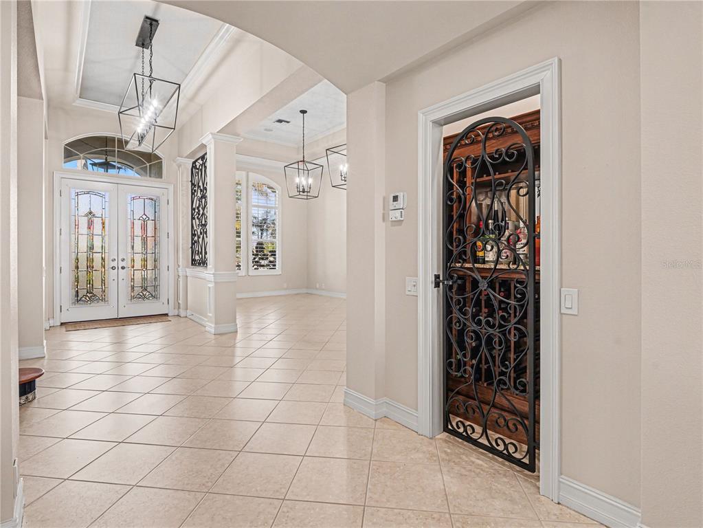 A spacious room with tile floors, two large pendant lights, and decorative iron wall paneling — 102 12TH AVENUE E, PALMETTO, FL