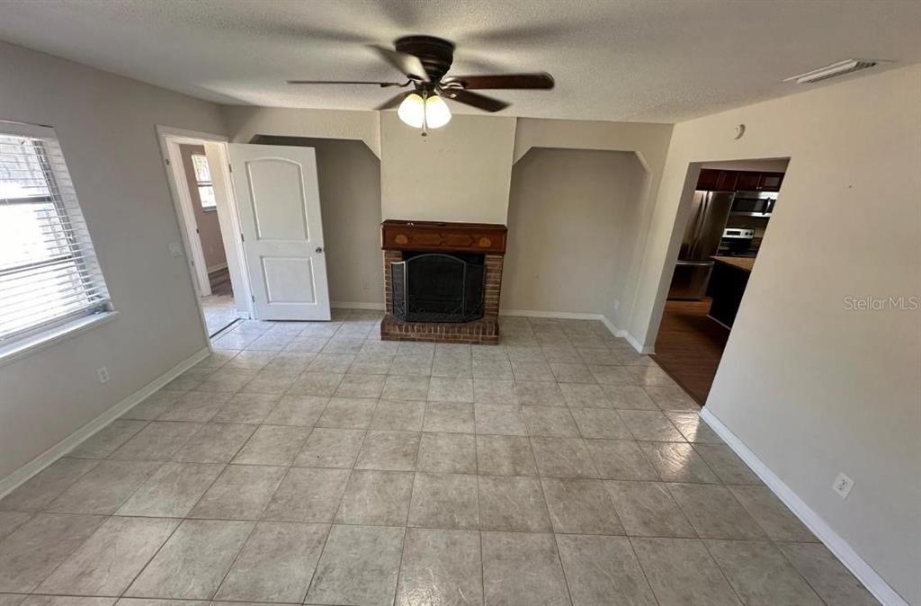 A living room features tile flooring, a brick fireplace, and a ceiling fan — 2211 SUNNY VIEW DR, OVIEDO, FL