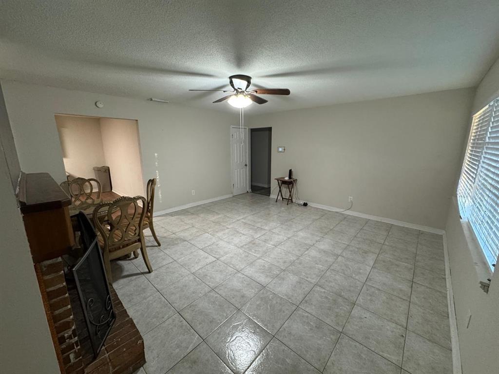 A living room with light tile flooring, a ceiling fan, and a brick fireplace — 2211 SUNNY VIEW DR, OVIEDO, FL
