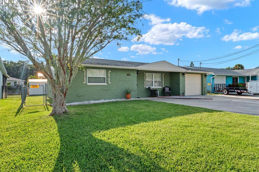A single-story green brick house with a front lawn, a tree, and an attached garage — 8505 OLD POST ROAD, PORT RICHEY, FL