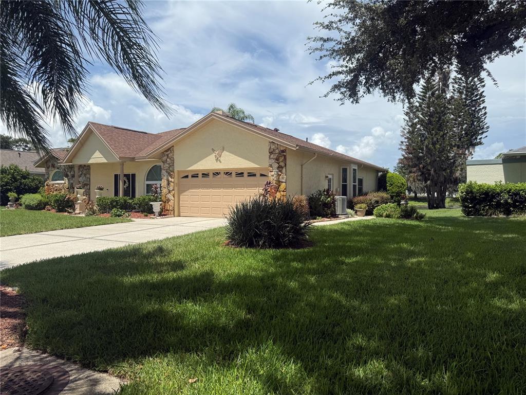 A single-story house with a stone facade, a two-car garage, and a manicured front lawn — 23427 PINE LAKE STREET, LAND O LAKES, FL