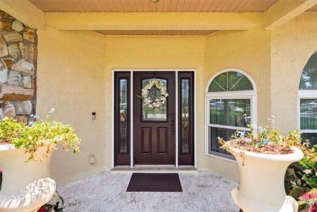 A single-story yellow house with a stone-accented garage and a concrete driveway — 23427 PINE LAKE STREET, LAND O LAKES, FL