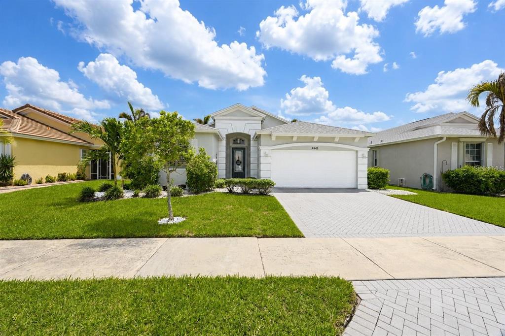 A single-story house with a white garage, a paved driveway, and a landscaped front yard — 468 SW TALQUIN LANE, PORT ST LUCIE, FL