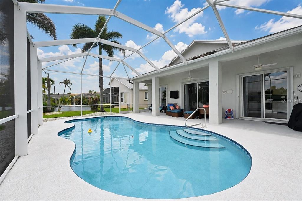 A screened-in patio features a swimming pool with steps and a view of a lake — 468 SW TALQUIN LANE, PORT ST LUCIE, FL