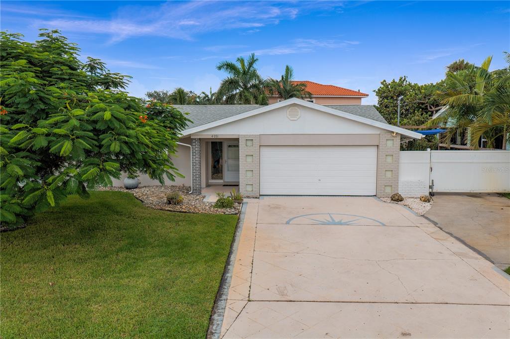 A single-story house with a white garage door, a concrete driveway, and a large green tree — 4051 14TH STREET NE, ST PETERSBURG, FL