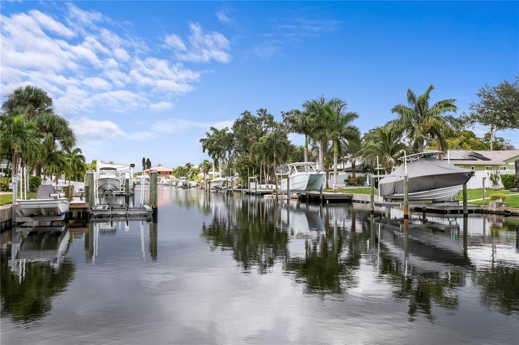 A canal view featuring several boats docked at private lifts along a residential shoreline — 4051 14TH STREET NE, ST PETERSBURG, FL