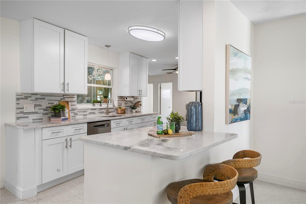 A paved patio features a wooden pergola, two blue Adirondack chairs, and a waterfront view — 4051 14TH STREET NE, ST PETERSBURG, FL