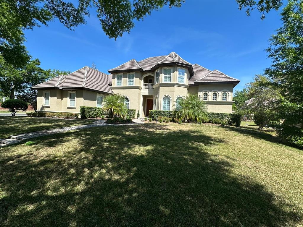 A large two-story stucco house with a tiled roof and a front lawn — 8734 CRESTGATE CIRCLE, ORLANDO, FL