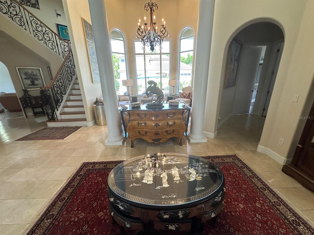 A grand foyer features a circular coffee table, a staircase, and large windows between columns — 8734 CRESTGATE CIRCLE, ORLANDO, FL