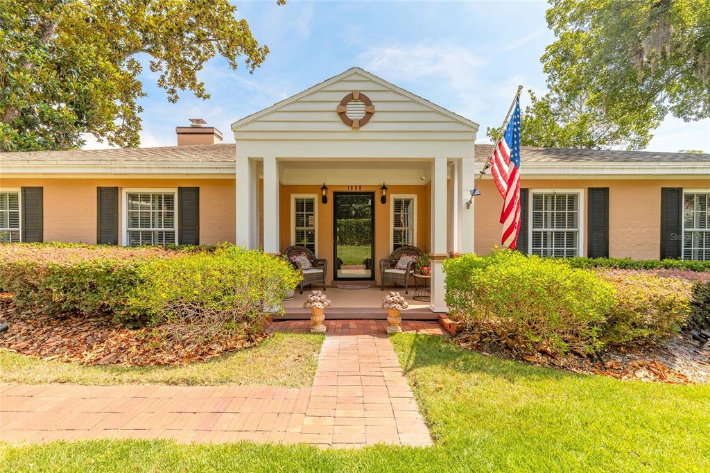 A single-story house with a brick walkway leading to a covered porch and American flag — 1600 S PENNSYLVANIA AVENUE, WINTER PARK, FL