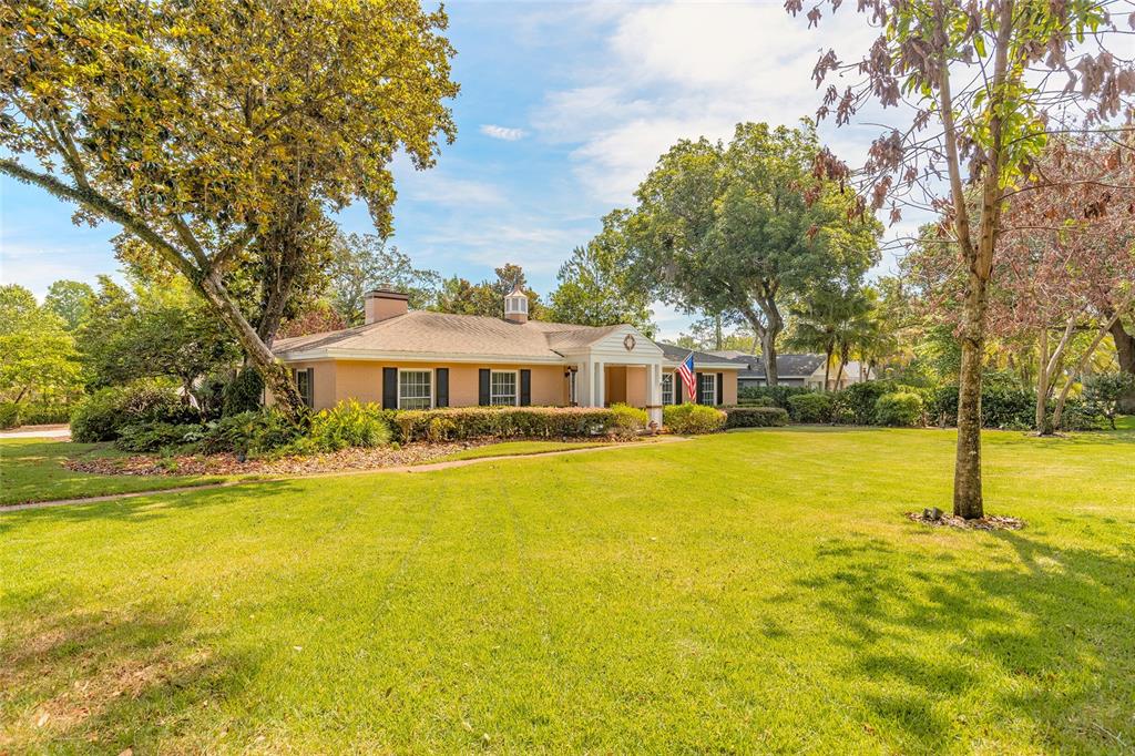 A single-story tan house with a white front entrance sits behind a large green lawn — 1600 S PENNSYLVANIA AVENUE, WINTER PARK, FL
