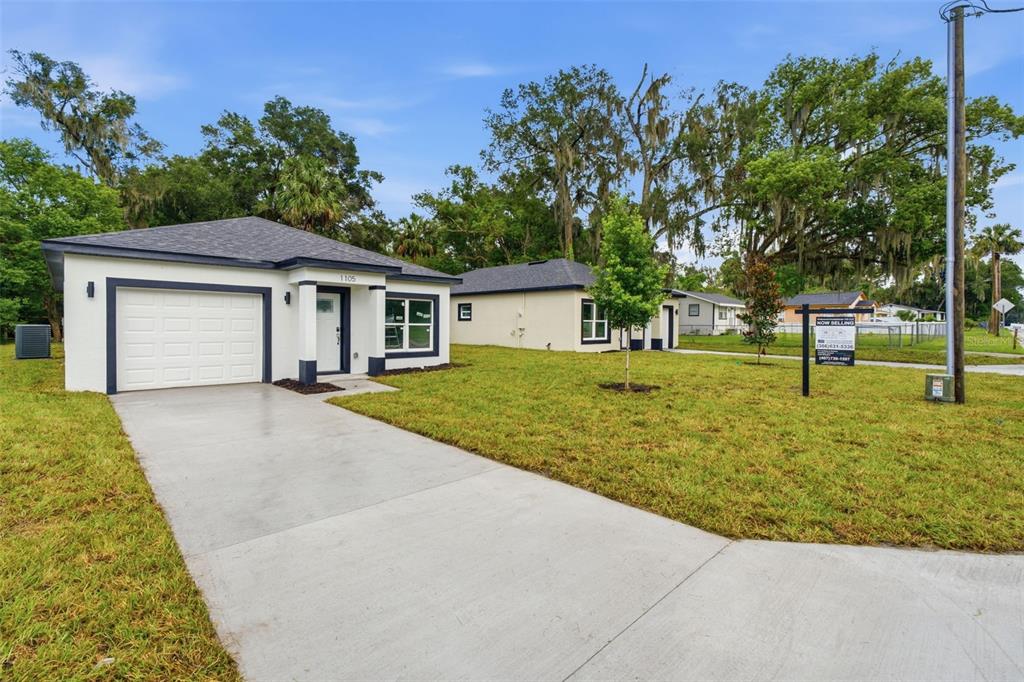A modern single-story house with a white stucco exterior, dark trim, and a concrete driveway — 1105 S ADELLE AVENUE, DELAND, FL