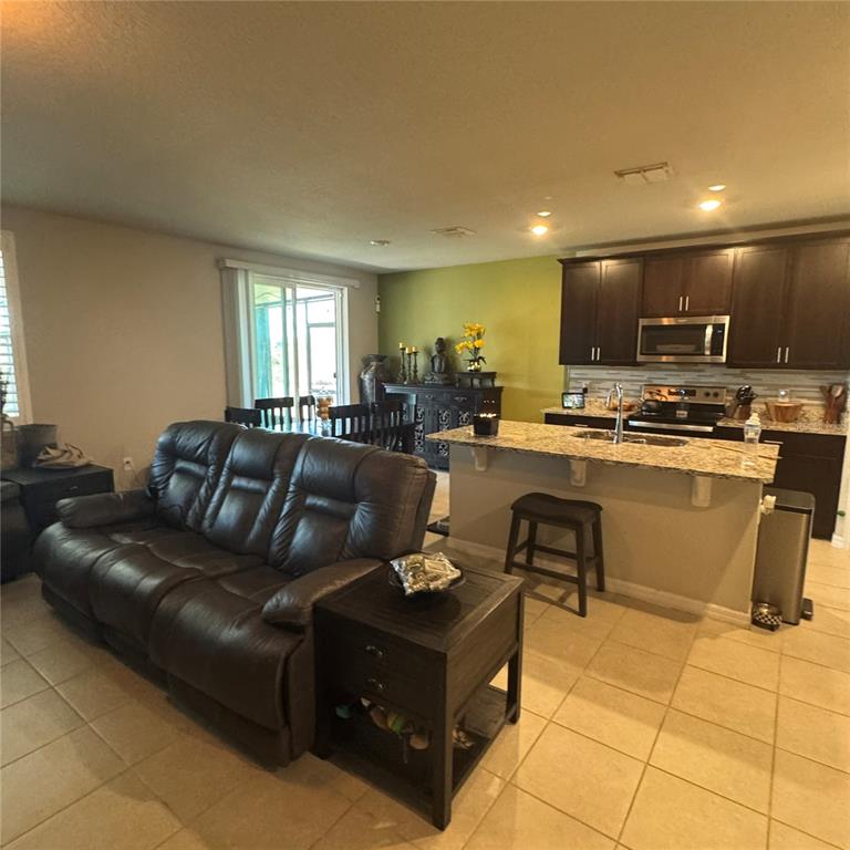 A kitchen features white cabinetry, a central island with seating, and a patterned tile backsplash — 17268 CAGAN CROSSINGS BOULEVARD, CLERMONT, FL
