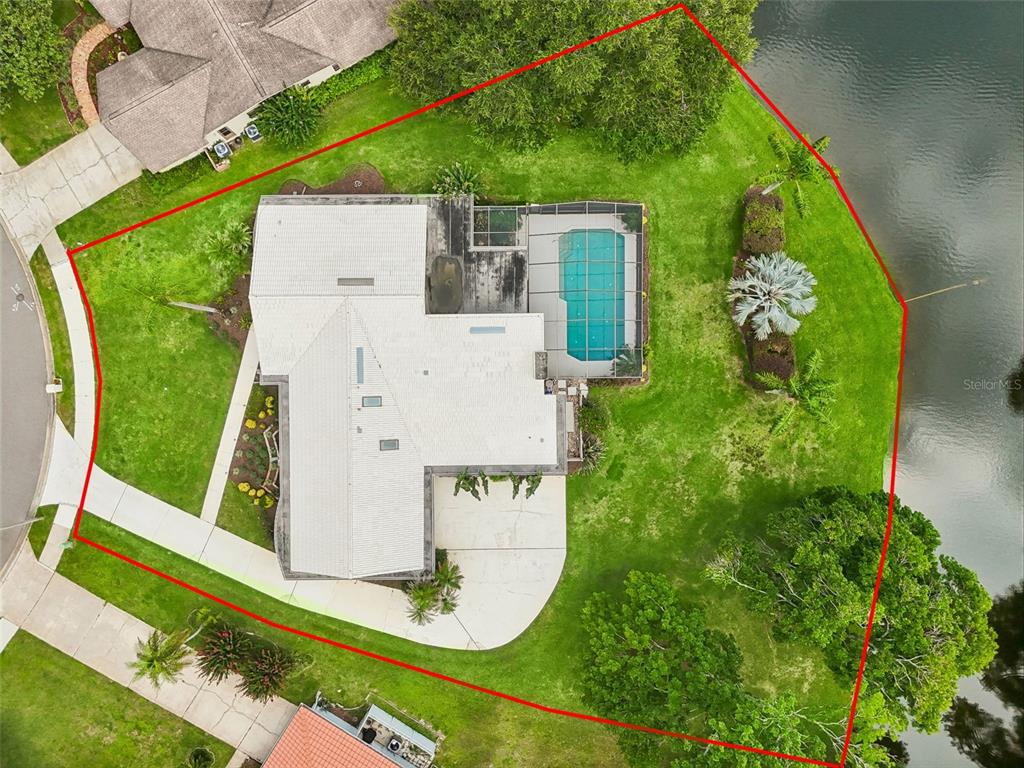 An aerial view shows a house with a pool enclosure on a waterfront lot — 2364 VIOLET PL, PALM HARBOR, FL