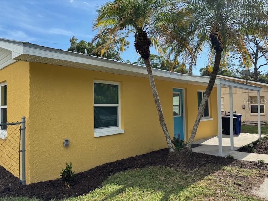 A yellow exterior house with a blue door, palm trees, and a small covered porch — 537 CAPITOL STREET, NORTH FORT MYERS, FL