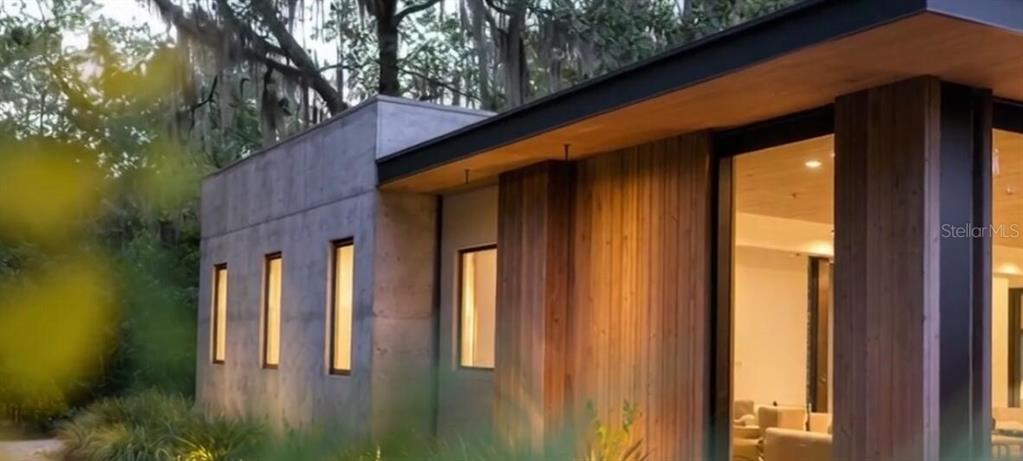 The exterior of a modern home features concrete walls, vertical wood siding, and large windows — 936 PARADISE BOULEVARD, GEORGETOWN, FL