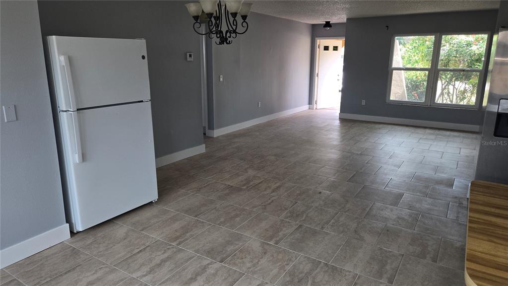 A kitchen and dining area features a white refrigerator, tiled floors, and a chandelier — 347 HOLLY ROAD, VENICE, FL