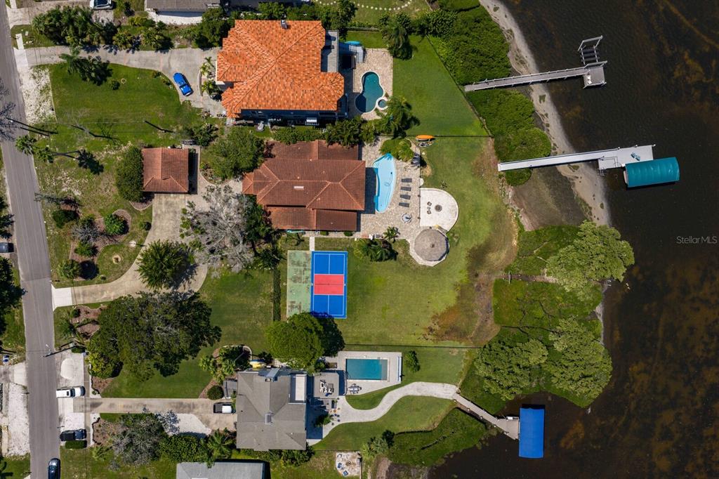 An aerial view of a backyard featuring a swimming pool, tiki hut, and pickleball court — 1632 SEA BREEZE DRIVE, TARPON SPRINGS, FL