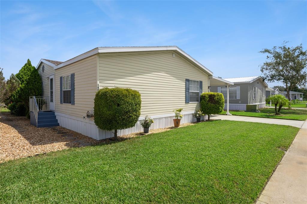 A light yellow manufactured home with a front porch and a manicured lawn — 14019 ROYAL FERN WAY, ASTATULA, FL