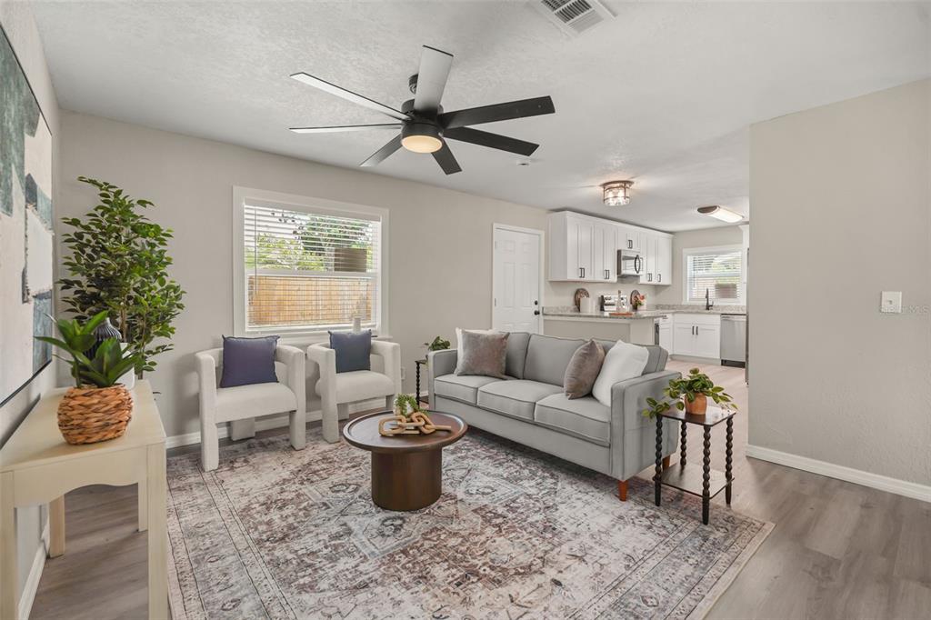 A living room with a gray sofa, two armchairs, a coffee table, and an open kitchen — 116 HARBOR DRIVE, WINTER HAVEN, FL