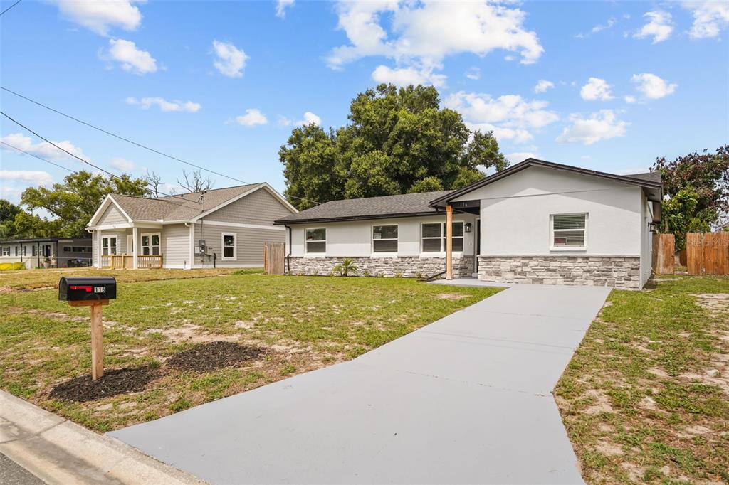 A single-story house with a white exterior, stone veneer, and a gray concrete walkway — 116 HARBOR DRIVE, WINTER HAVEN, FL