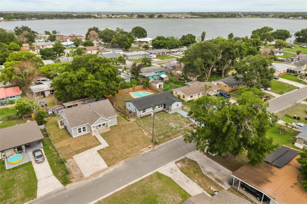 An aerial view shows two residential houses with yards, a swimming pool, and a nearby lake — 116 HARBOR DRIVE, WINTER HAVEN, FL