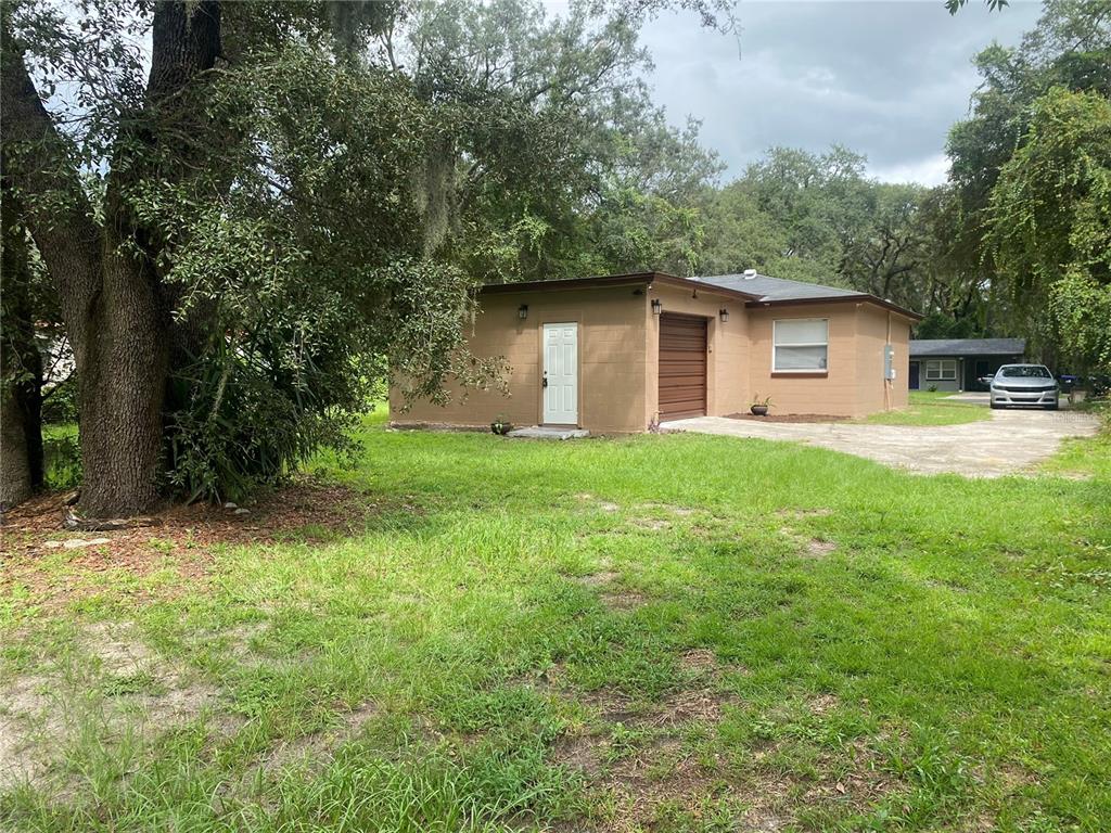 A tan concrete block detached garage with a white door and brown roll-up door — 1608 LONG LANE, APOPKA, FL