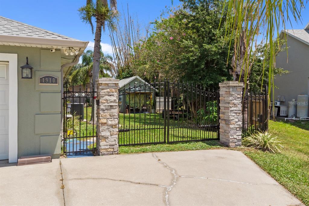 A concrete driveway leads to a black metal gate flanked by stone pillars — 1910 LEE WOOD COURT, ST CLOUD, FL